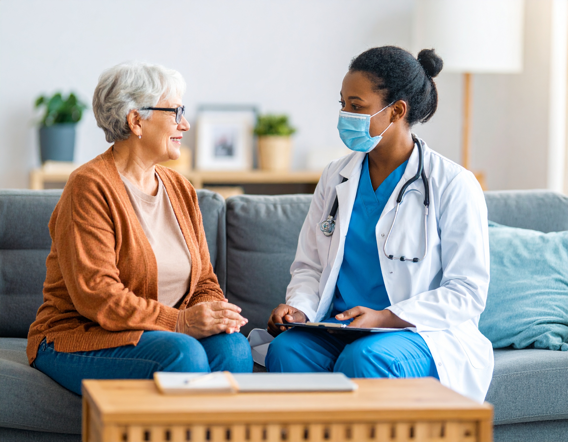 Black nurse practitioner speaking with an older adult patient in a home setting
